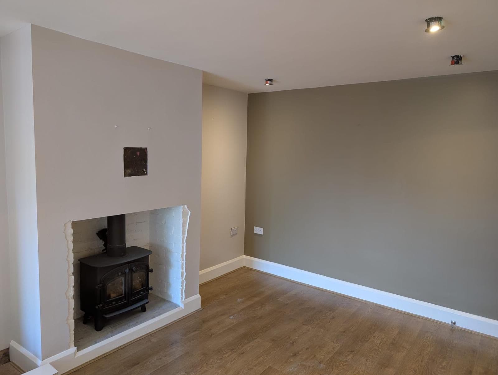 Living room with two-tone painted walls, wood burner fireplace and oak flooring
