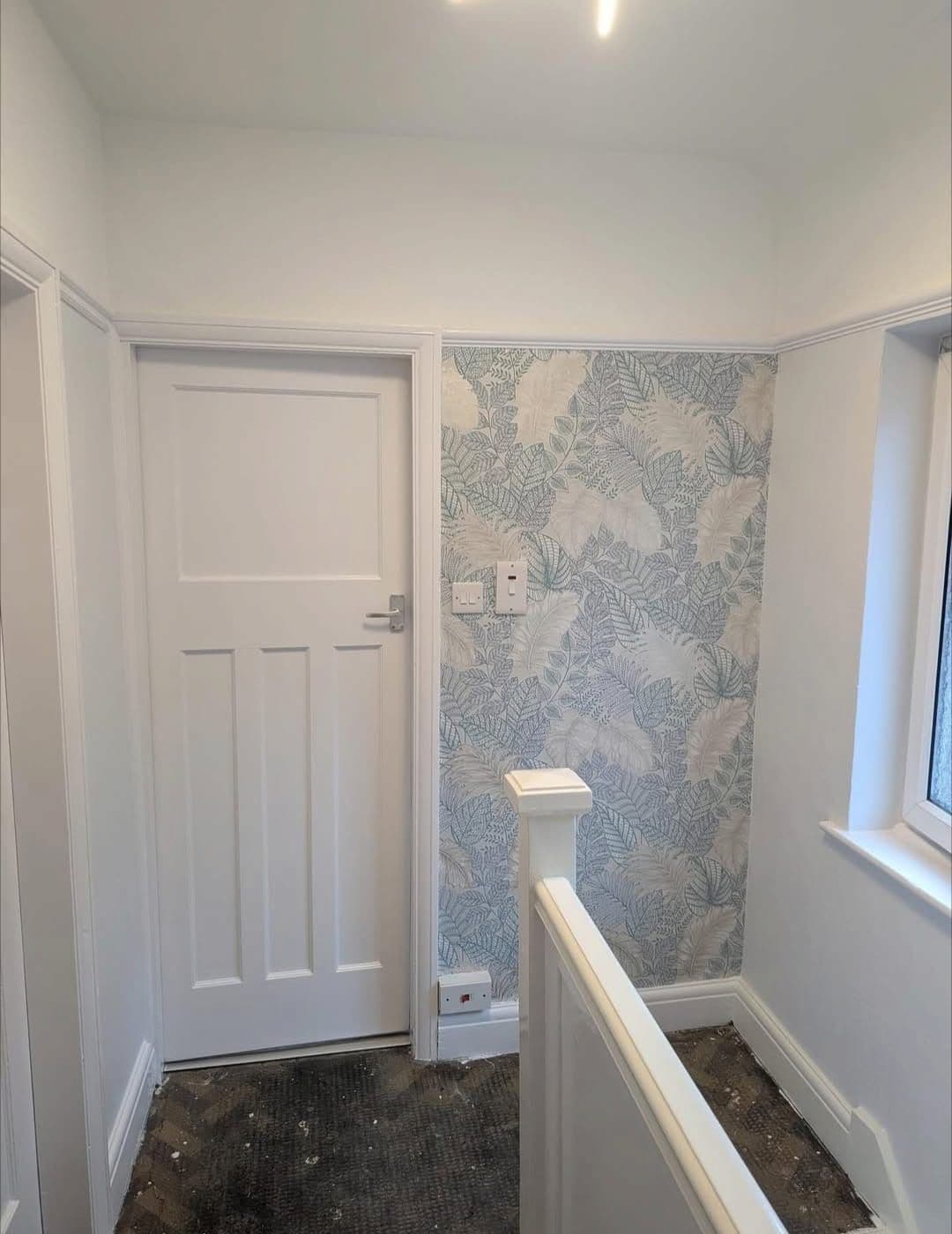 Landing with leaf pattern wallpaper and white painted door